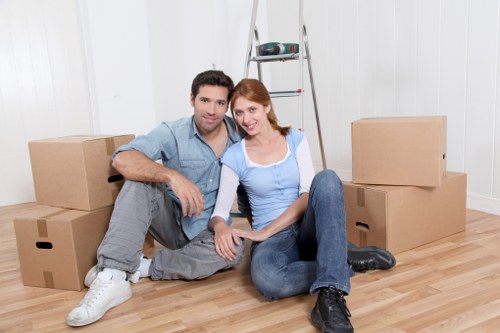 Professional movers carrying furniture near a Brent apartment building