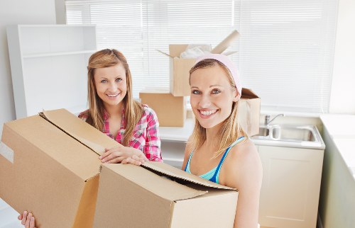Removalists carrying furniture through a Brent flat entrance with care